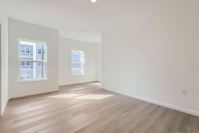 spare room with baseboards and light wood finished floors