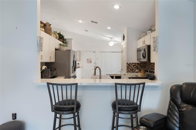 130 Bloomingdale Dr, Davenport, FL 33897 - kitchen featuring stainless steel appliances, a peninsula, tasteful backsplash, white cabinets, and ceiling fan