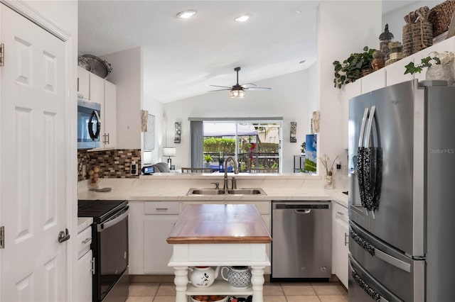130 Bloomingdale Dr, Davenport, FL 33897 - kitchen with stainless steel appliances, a sink, lofted ceiling, white cabinetry, and tasteful backsplash
