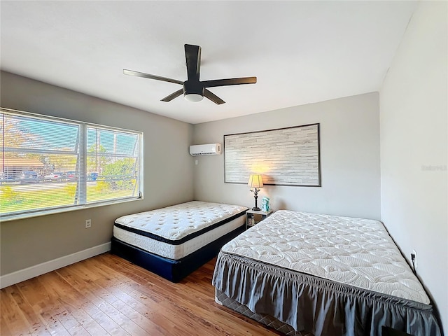 bedroom with hardwood / wood-style floors, a wall mounted air conditioner, and ceiling fan