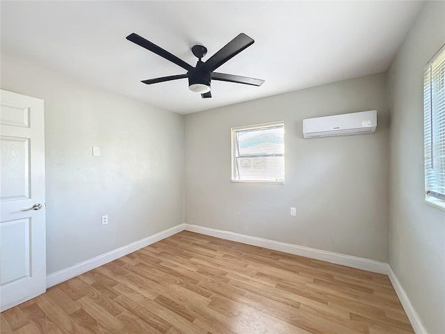 spare room featuring a wall mounted air conditioner, ceiling fan, and light hardwood / wood-style flooring