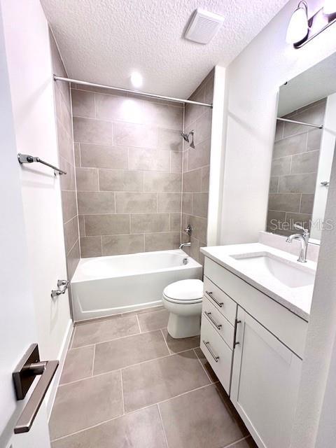 3225 Cup Dr, Lakeland, FL 33803 - full bath with a textured ceiling,  shower combination, tile patterned flooring, toilet, and vanity