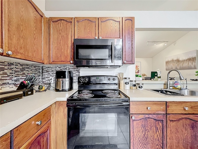 kitchen featuring brown cabinets, light countertops, stainless steel microwave, electric range, and a sink