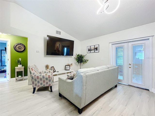 living area featuring vaulted ceiling, french doors, light wood-type flooring, and visible vents