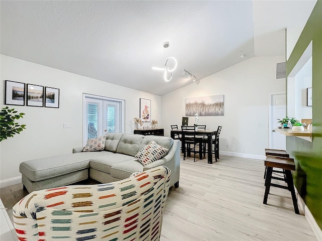 living area with lofted ceiling, a textured ceiling, light wood-style flooring, baseboards, and french doors