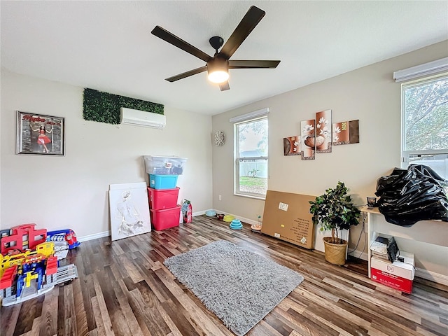 recreation room featuring a wall mounted air conditioner, wood finished floors, and baseboards