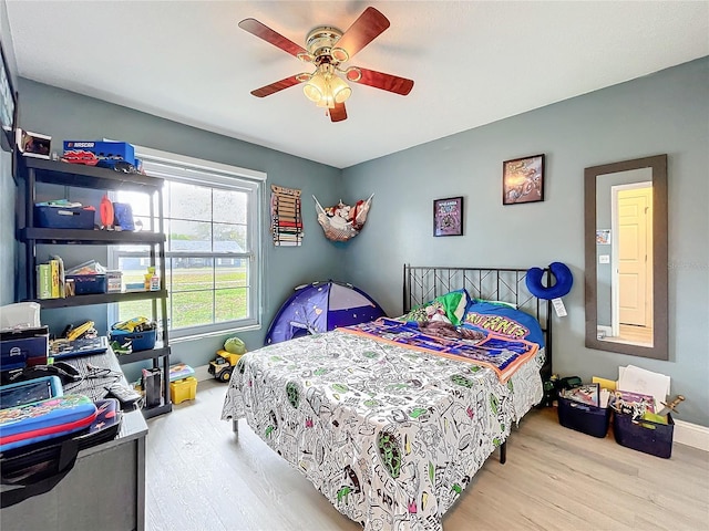 bedroom with ceiling fan, baseboards, and wood finished floors