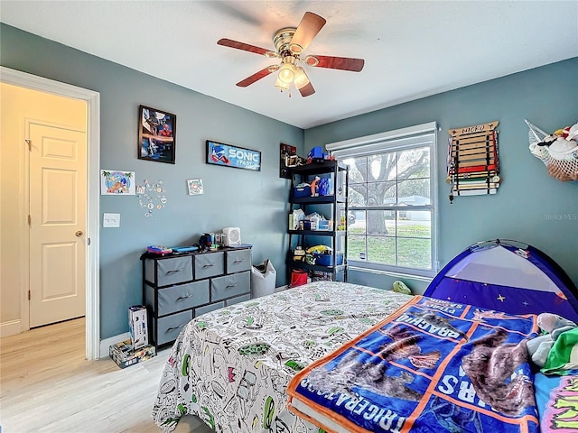 bedroom with a ceiling fan, baseboards, and wood finished floors