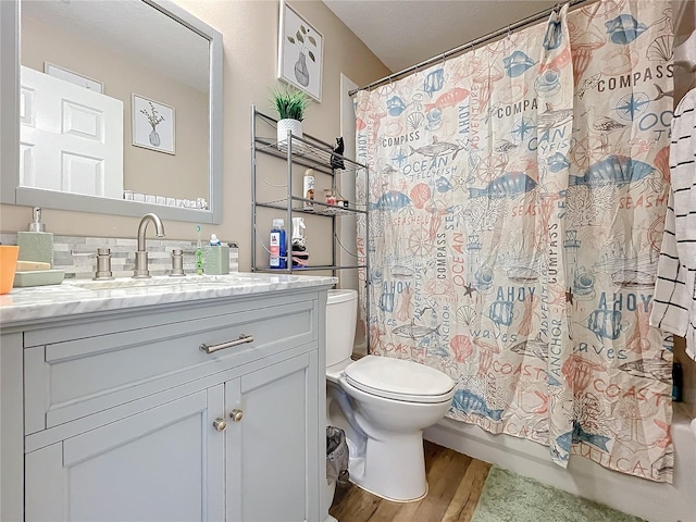 bathroom featuring toilet, shower / bathtub combination with curtain, wood finished floors, and vanity