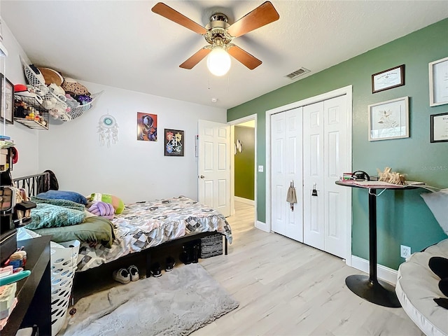 bedroom featuring light wood finished floors, a closet, visible vents, ceiling fan, and baseboards