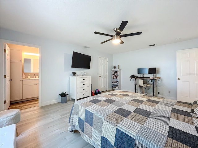 bedroom with light wood finished floors, baseboards, visible vents, ceiling fan, and a sink