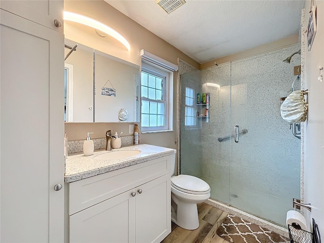 bathroom with visible vents, toilet, a stall shower, a textured ceiling, and wood finished floors