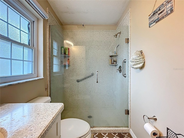 full bathroom featuring a textured ceiling, vanity, a shower stall, and toilet