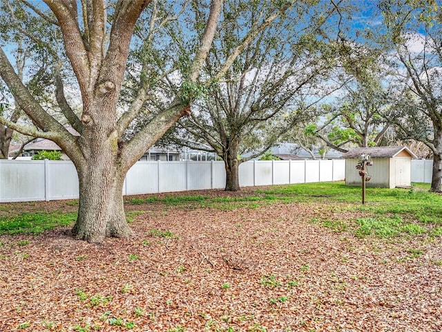 view of yard with a shed, a fenced backyard, and an outbuilding