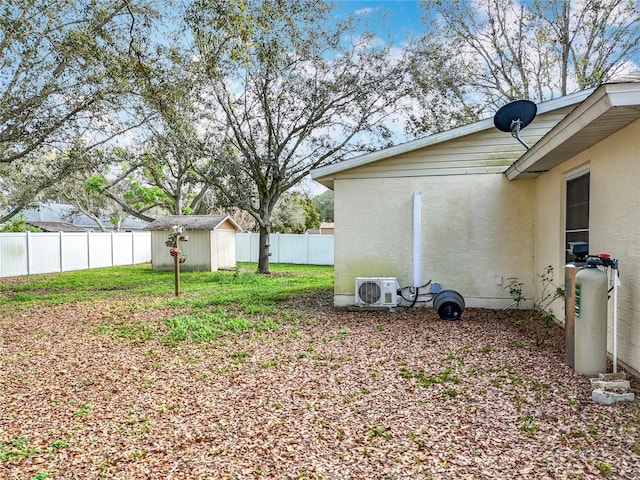 view of yard with ac unit, an outbuilding, a fenced backyard, and a storage unit