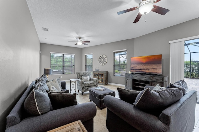 living room with light tile patterned floors, visible vents, ceiling fan, a textured ceiling, and baseboards