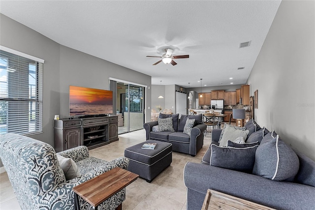 living room with visible vents, ceiling fan, and a textured ceiling