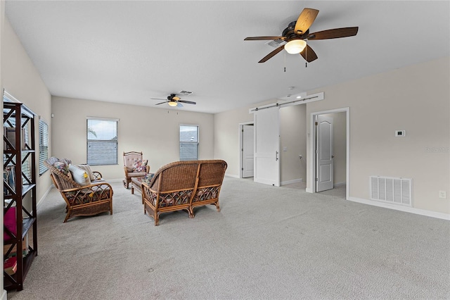 living area with a barn door, visible vents, baseboards, and light colored carpet