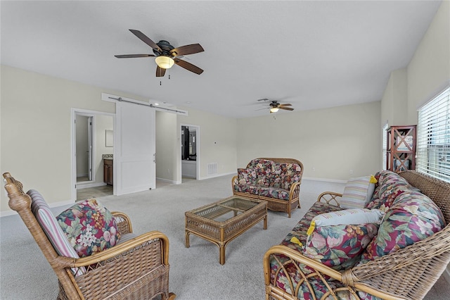 living room with light carpet, a barn door, baseboards, and a ceiling fan