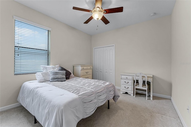 bedroom with a ceiling fan, baseboards, a closet, and light colored carpet