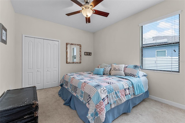 bedroom featuring baseboards, ceiling fan, a closet, and light colored carpet