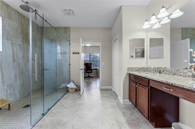 full bathroom featuring a stall shower, vanity, visible vents, and baseboards