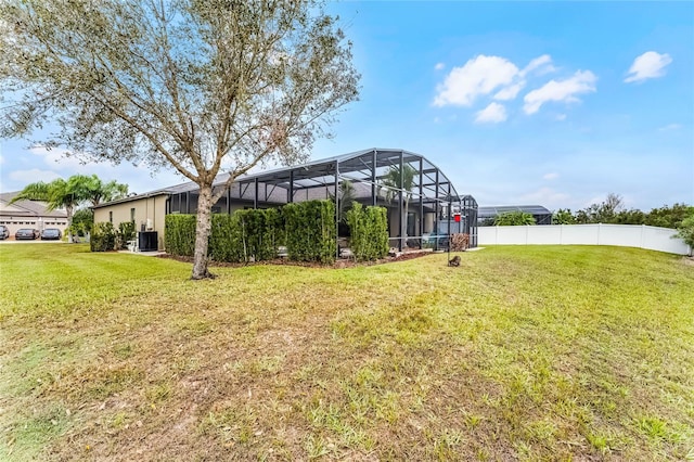 view of yard with glass enclosure and fence