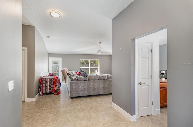 living room featuring a ceiling fan, lofted ceiling, and baseboards