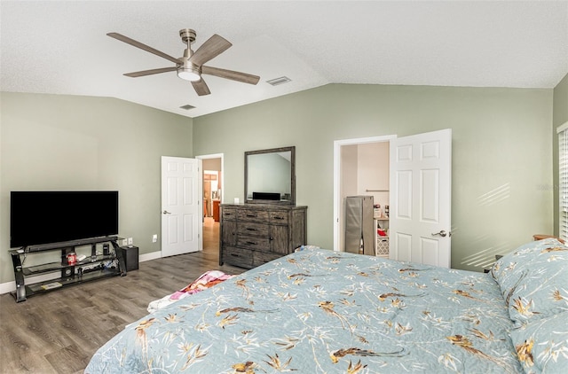 bedroom with ceiling fan, visible vents, vaulted ceiling, and wood finished floors