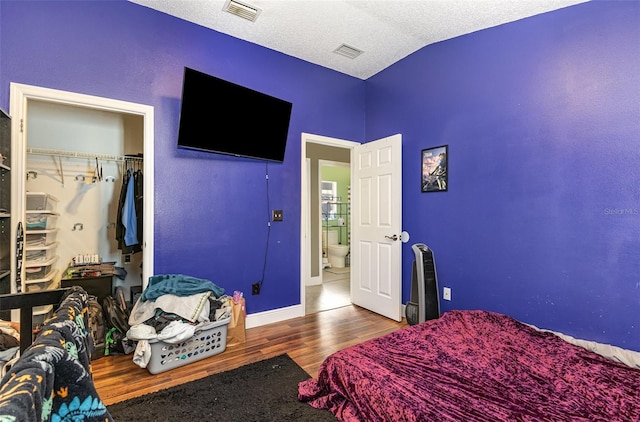 bedroom featuring lofted ceiling, visible vents, a textured ceiling, and wood finished floors