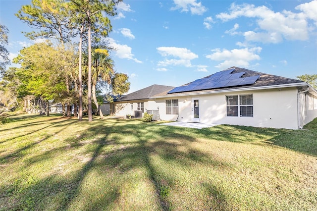 back of property featuring a patio area, stucco siding, solar panels, and a yard