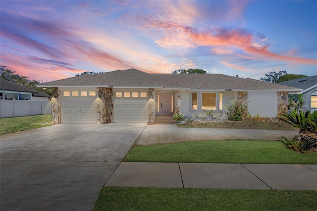 view of front of house with stucco siding, fence, a garage, stone siding, and driveway