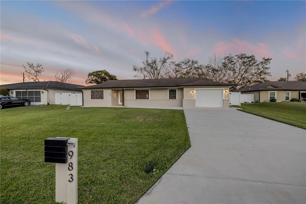 ranch-style house featuring a yard, driveway, and a garage