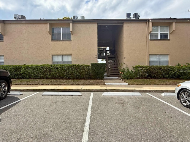 view of property featuring uncovered parking and stairway