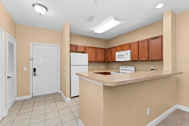 kitchen with white appliances, light tile patterned floors, and kitchen peninsula