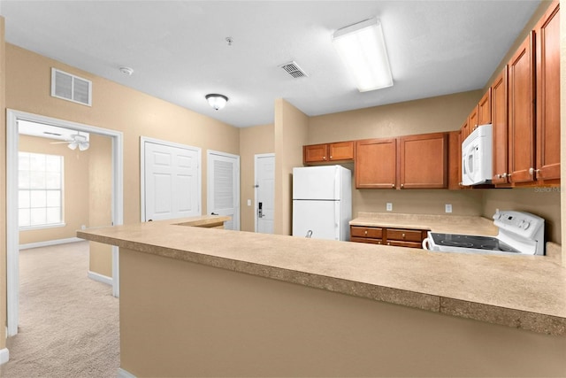 kitchen featuring white appliances, light carpet, ceiling fan, and kitchen peninsula