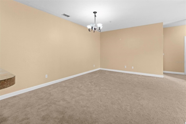 carpeted spare room with a notable chandelier