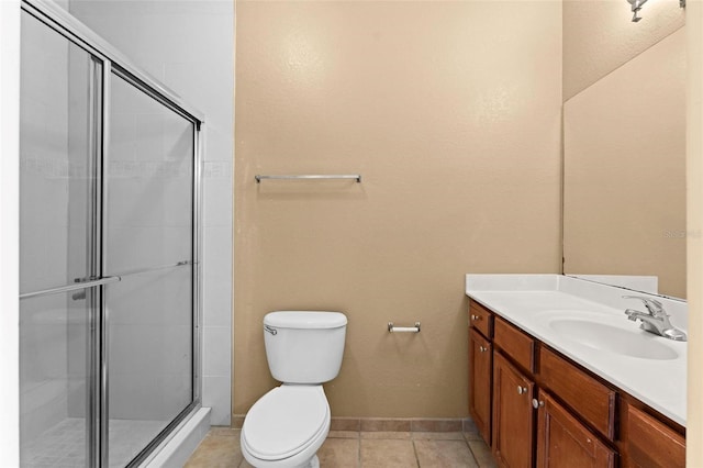 bathroom featuring toilet, vanity, tile patterned flooring, and a shower with shower door