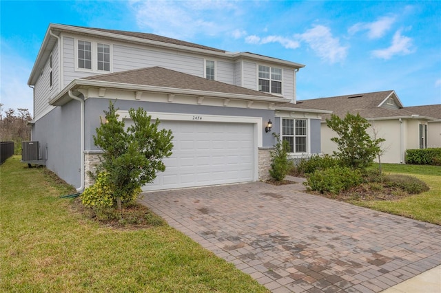 view of front of house featuring central AC unit, an attached garage, stone siding, decorative driveway, and a front lawn