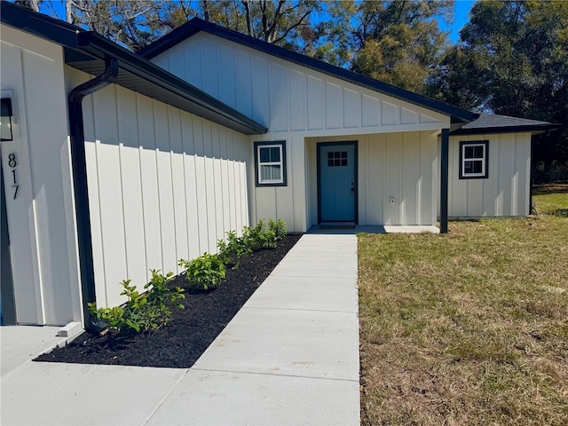 property entrance featuring board and batten siding and a lawn