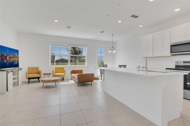 1620 Pelican Dr, Davenport, FL 33896 - kitchen with appliances with stainless steel finishes, hanging light fixtures, an island with sink, white cabinets, and sink