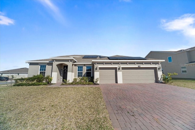 view of front of property featuring a garage, a front lawn, decorative driveway, and stucco siding