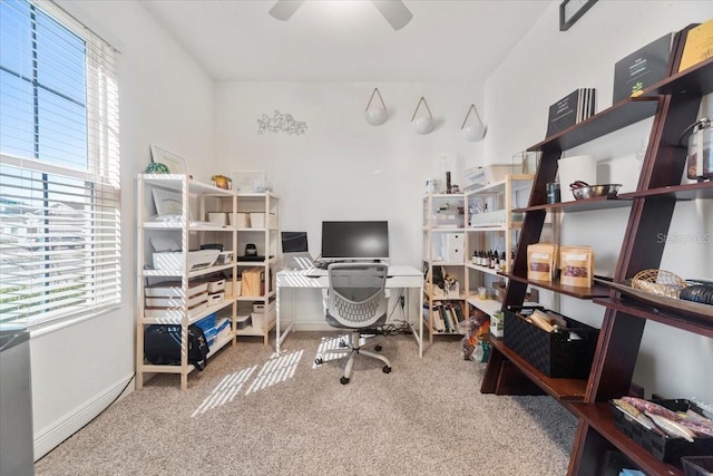 carpeted office space featuring a ceiling fan, plenty of natural light, and baseboards