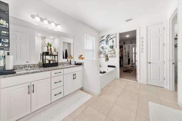 bathroom with tile patterned flooring, a garden tub, a sink, visible vents, and double vanity