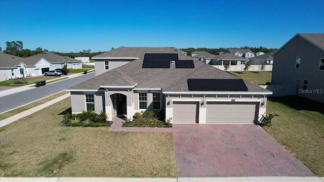 view of front of property featuring a front lawn, decorative driveway, a residential view, and roof mounted solar panels