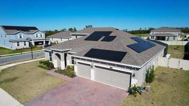 view of front of house with solar panels, a front yard, fence, and a residential view