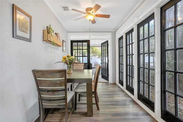 dining area featuring dark wood-style floors, ceiling fan, ornamental molding, and visible vents