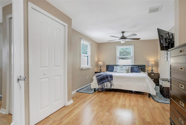 bedroom with ceiling fan, light wood finished floors, visible vents, and baseboards