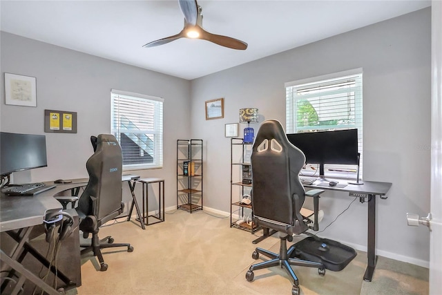 office space with a healthy amount of sunlight, ceiling fan, light carpet, and baseboards