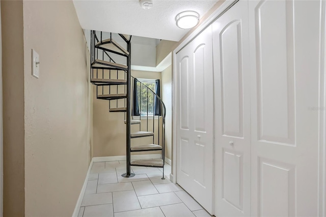 hallway with light tile patterned floors, stairs, baseboards, and a textured ceiling